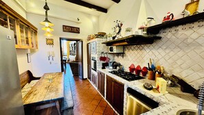 A kitchen with a wooden table, a stove, and a microwave. There is a sign on the wall that says "KITCHEN". - Roody Luxury house in Trastevere (Rome)