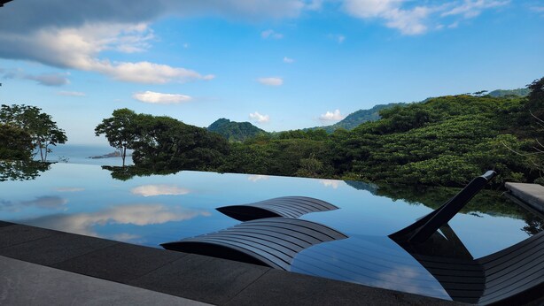 A serene infinity pool with a clear view of the sea and lush greenery in the background. - Spacious 5-bedroom ocean view villa in Dominicalito  (Puntarenas Province)