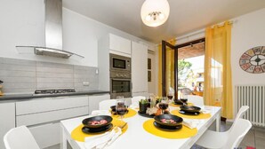 A modern kitchen with white cabinets, a stove, oven, and a dining area with a table set for four.