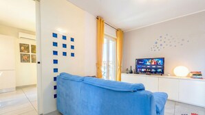 A modern living room with a blue sofa, a flat-screen TV, and a decorative wall with blue squares.