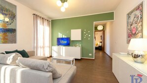A modern living room with a sofa, a TV, and a green accent wall.