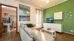 Un soggiorno con divano, tavolino, televisore e un quadro appeso al muro.
