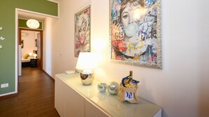 A hallway with a lamp, decorative items, and two large paintings on the wall.