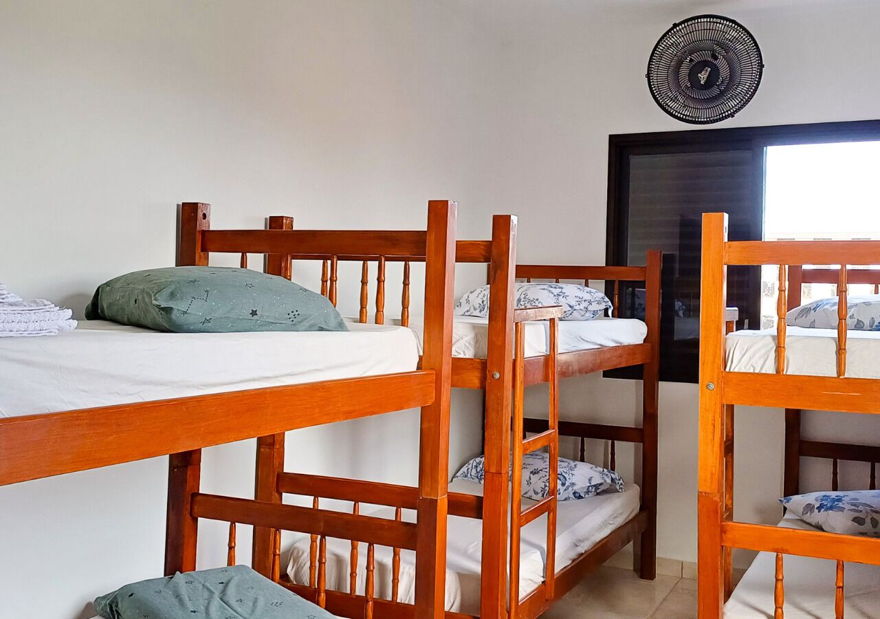 A room with bunk beds, a fan, and a window.