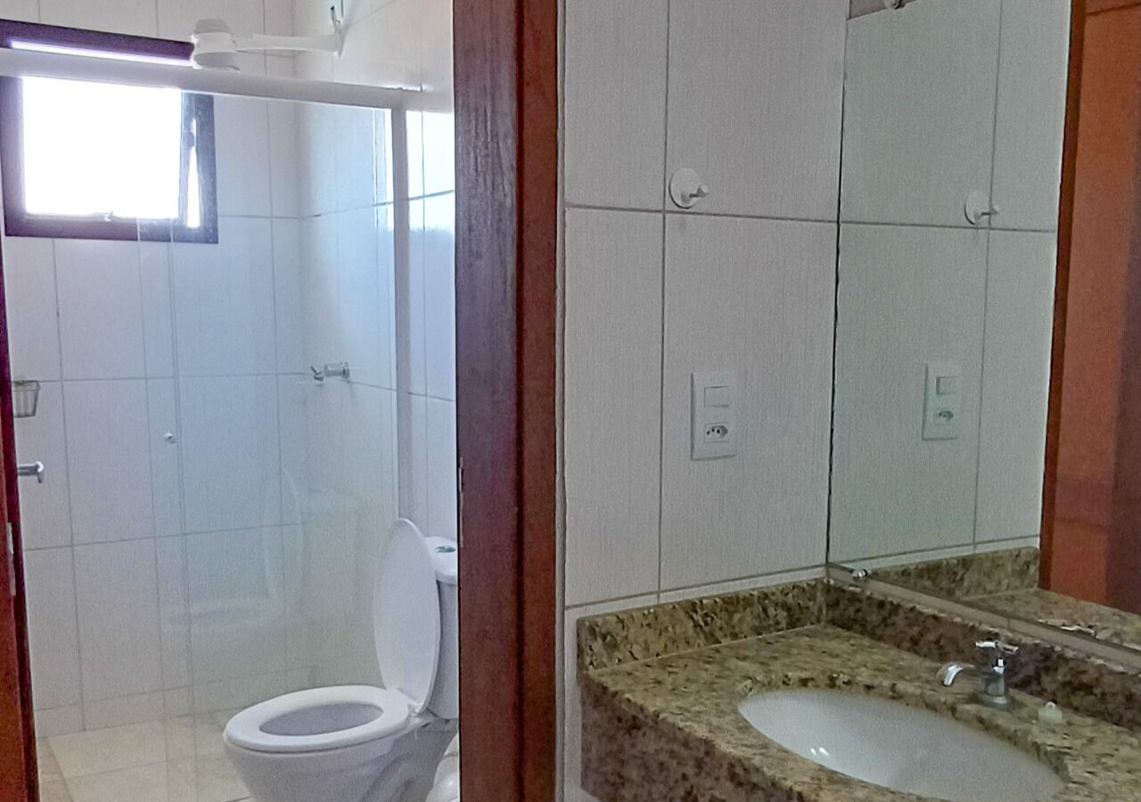 Un baño con inodoro, ducha y lavabo con encimera de granito.