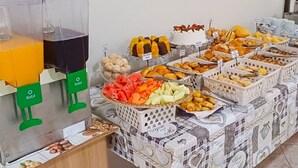 A buffet with various food items and a juice dispenser. - Pousada Nereidas (Guaratuba)