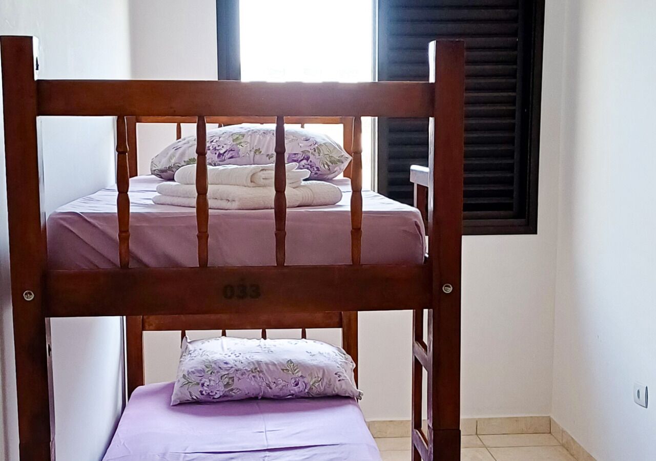Una cama litera con cabecera de madera y una cama inferior con un cojín estampado floral.
