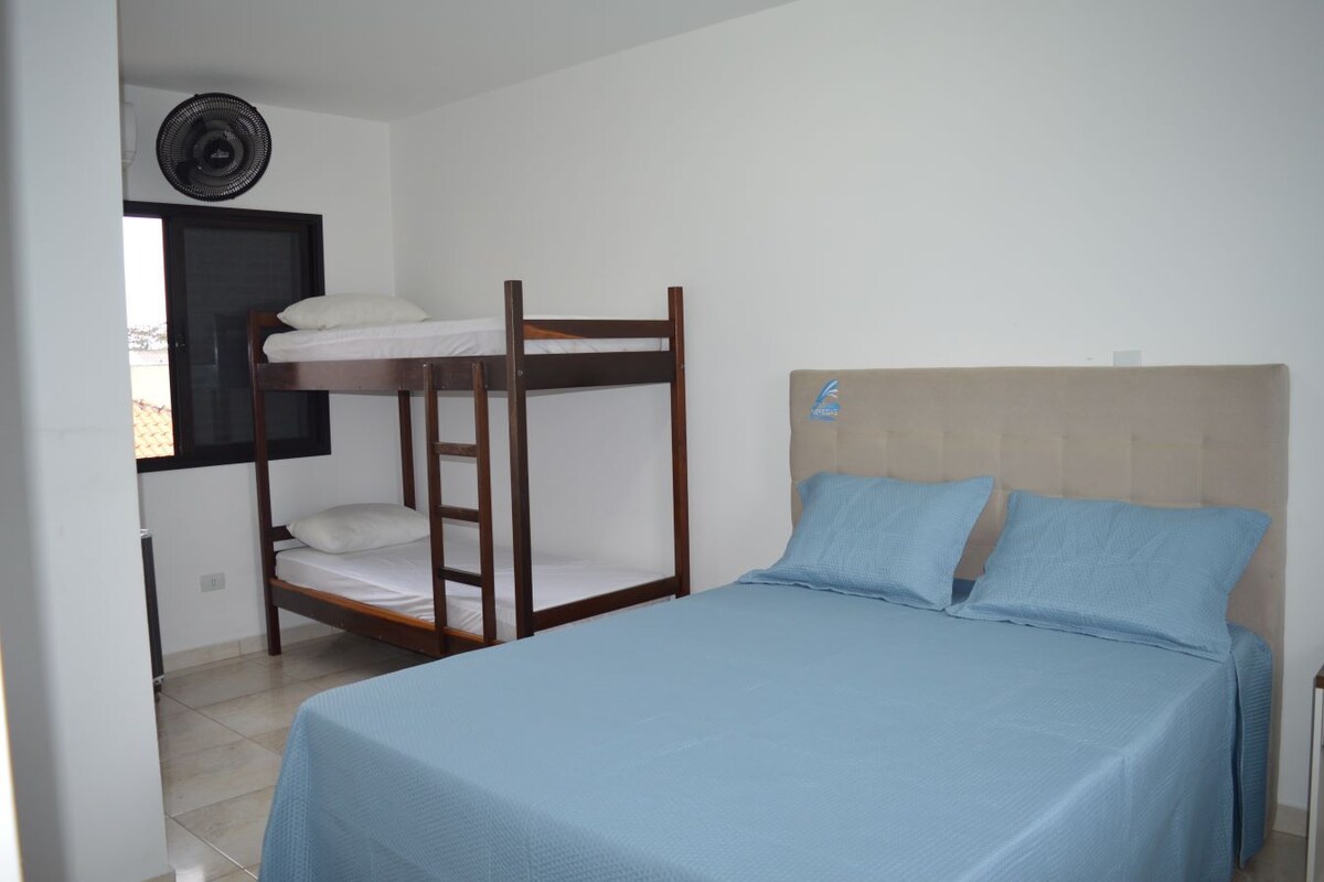 A bedroom with a bunk bed, a single bed, and a ceiling fan.