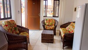 A room with wicker furniture, a door, and a view through a window. - Pousada Nereidas (Guaratuba)
