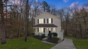 A two-story house with a front porch, surrounded by trees and a well-maintained lawn.