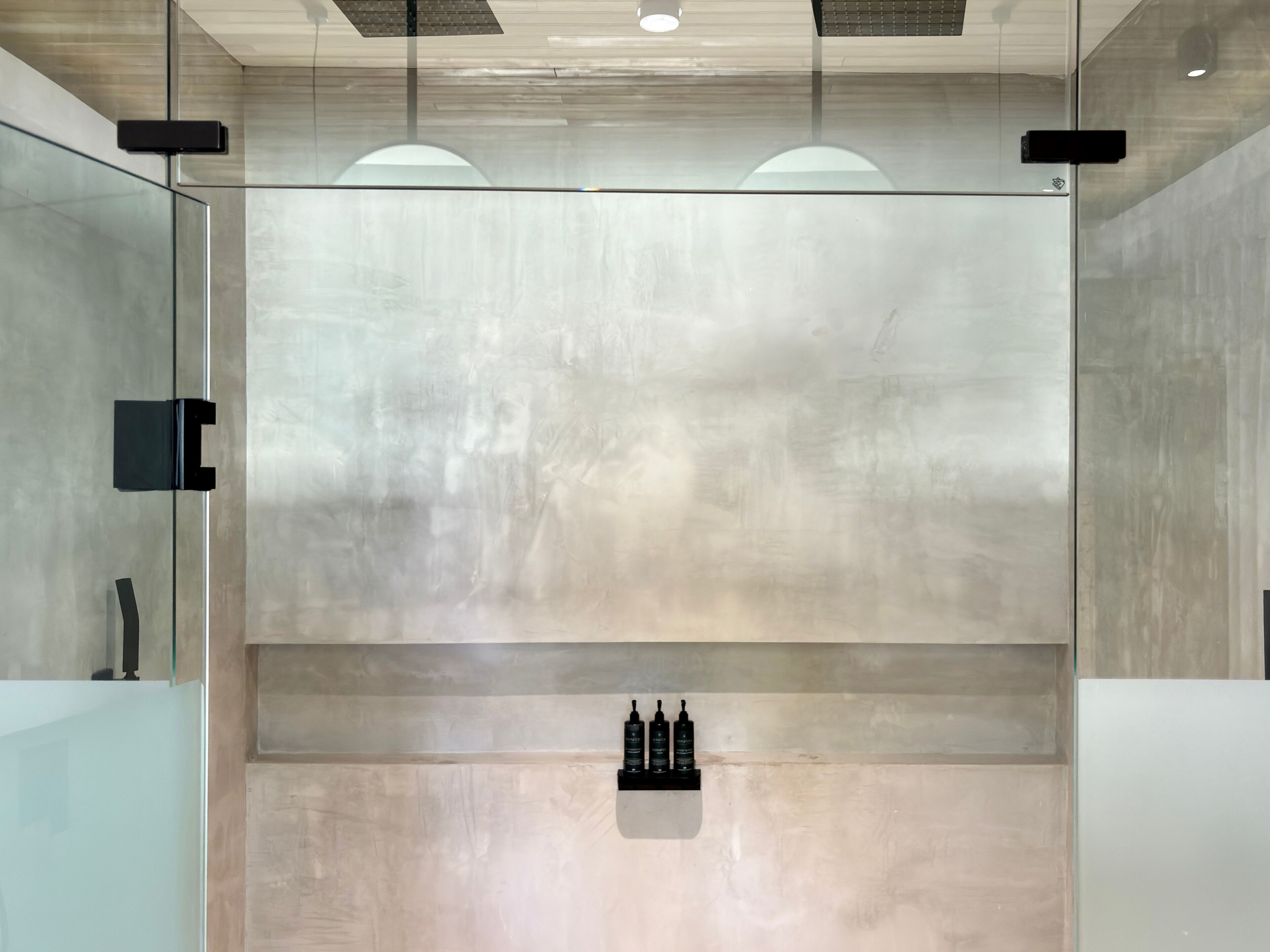 Un interior moderno con diseño minimalista, que incluye un separador de vidrio, un estante empotrado con botellas e iluminación empotrada en el techo.