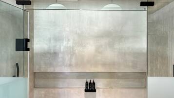 Un intérieur moderne au design minimaliste, avec une cloison en verre, une étagère encastrée où sont disposées des bouteilles et un plafond doté d’un éclairage indirect.