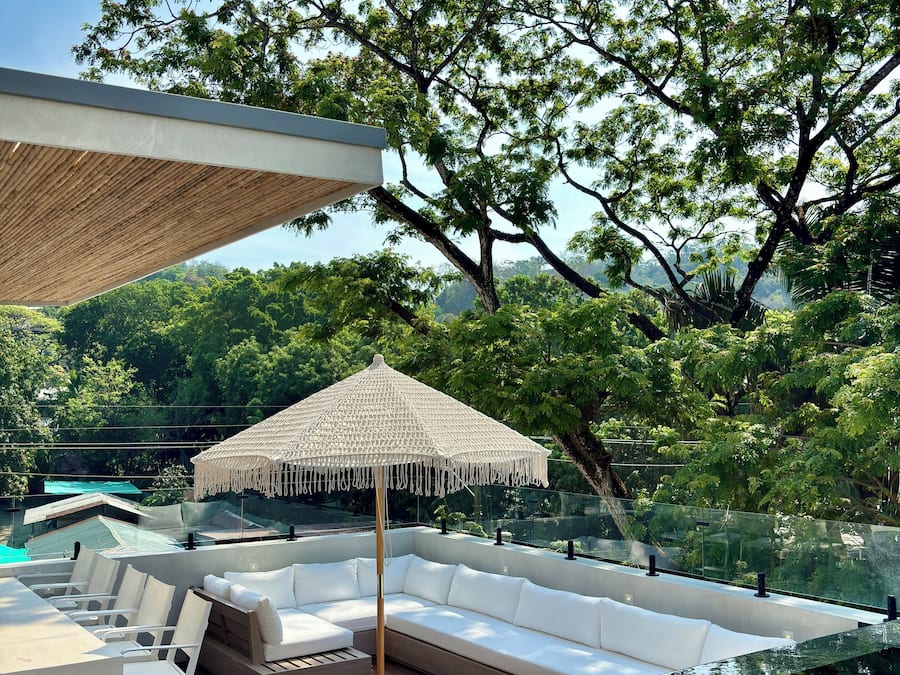 A poolside area with a white outdoor sofa, a hanging chair, and a canopy.