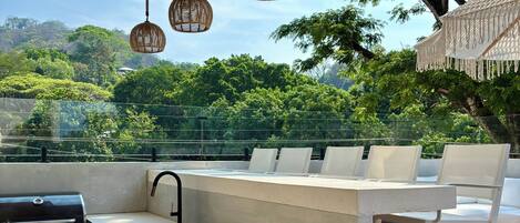 An outdoor kitchen area with a grill, sink, and seating.