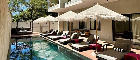 Een buitenzwembad, parasols bij het zwembad en ligstoelen