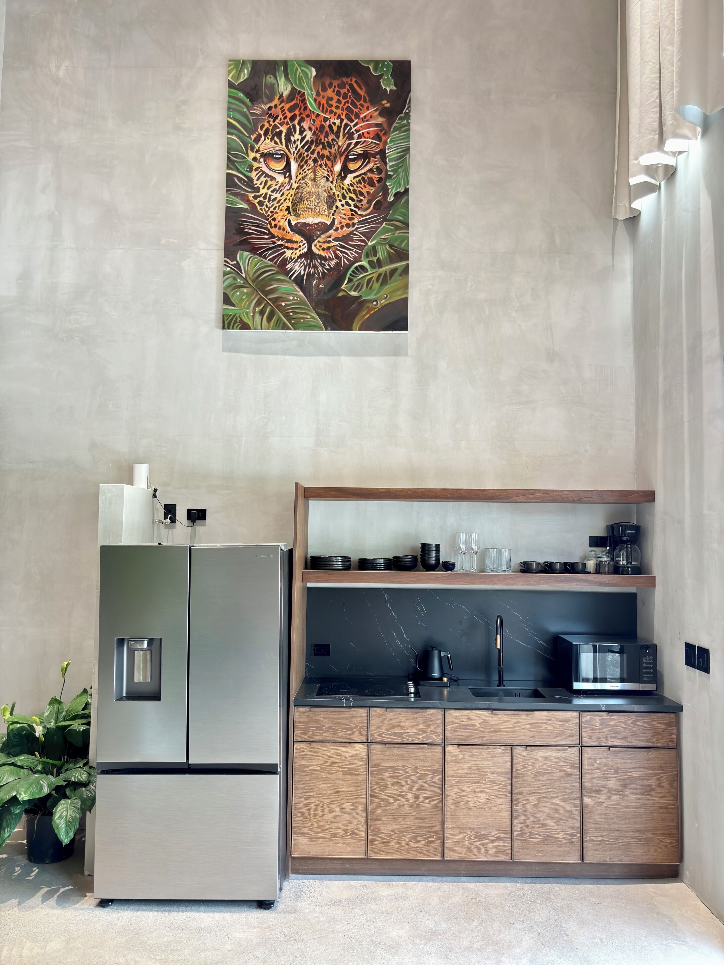 A modern kitchen with a stainless steel refrigerator, wooden cabinets, and a marble backsplash.