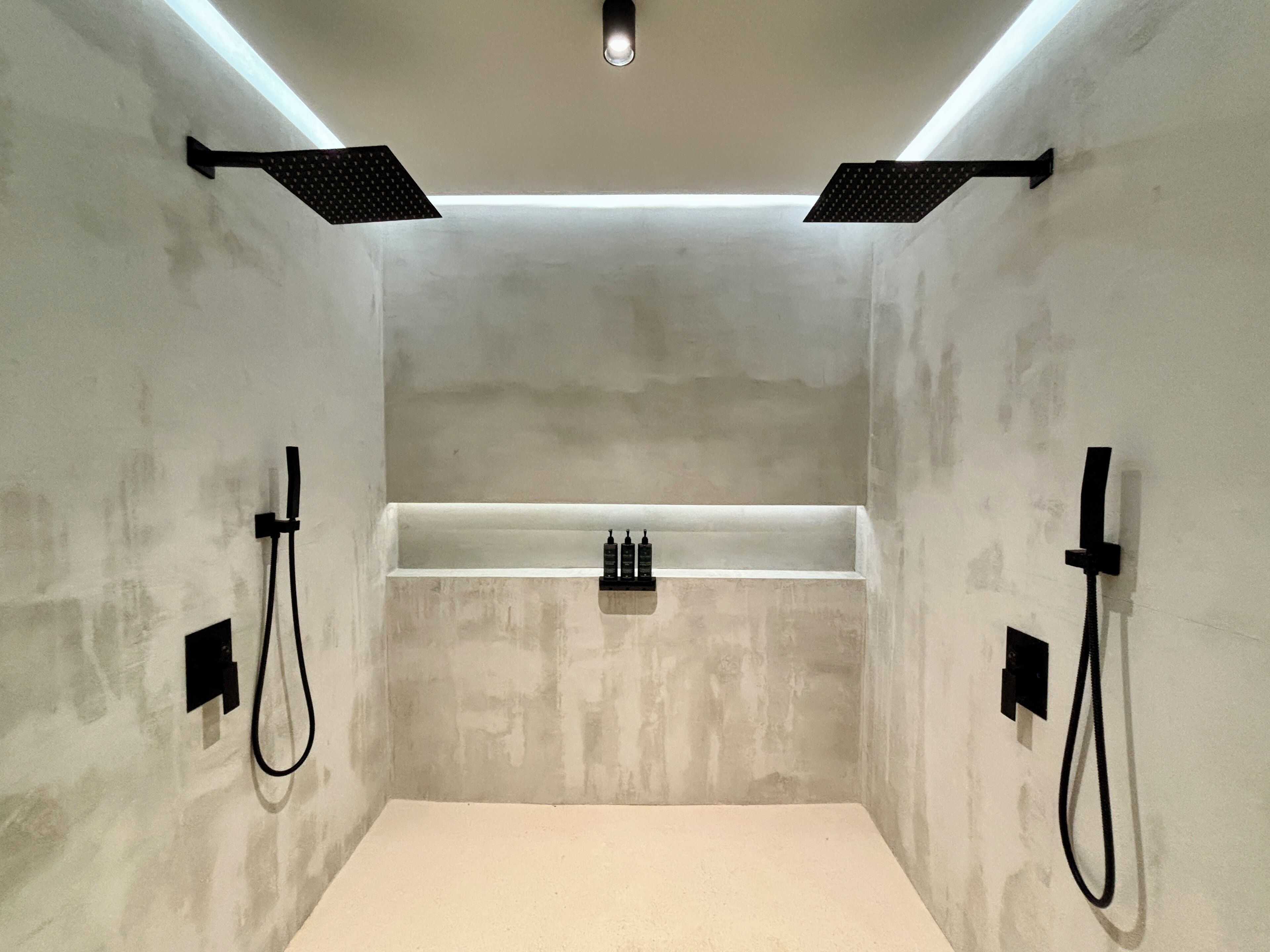 A modern bathroom with a built-in shower, a white bathtub, and black fixtures.