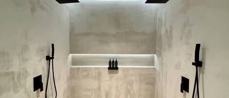 Un baño moderno con ducha integrada, una bañera blanca y accesorios negros.