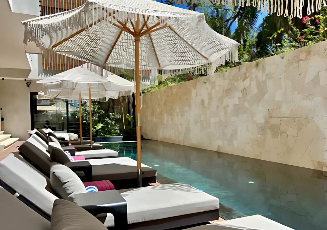 Uma área ao redor da piscina com espreguiçadeiras e guarda-sóis.