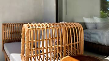 A wicker sofa with a woven backrest and a matching side table, positioned next to a window.