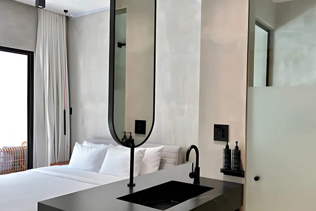 Une chambre d’hôtel moderne avec un grand lit, un lavabo intégré et un miroir au-dessus.