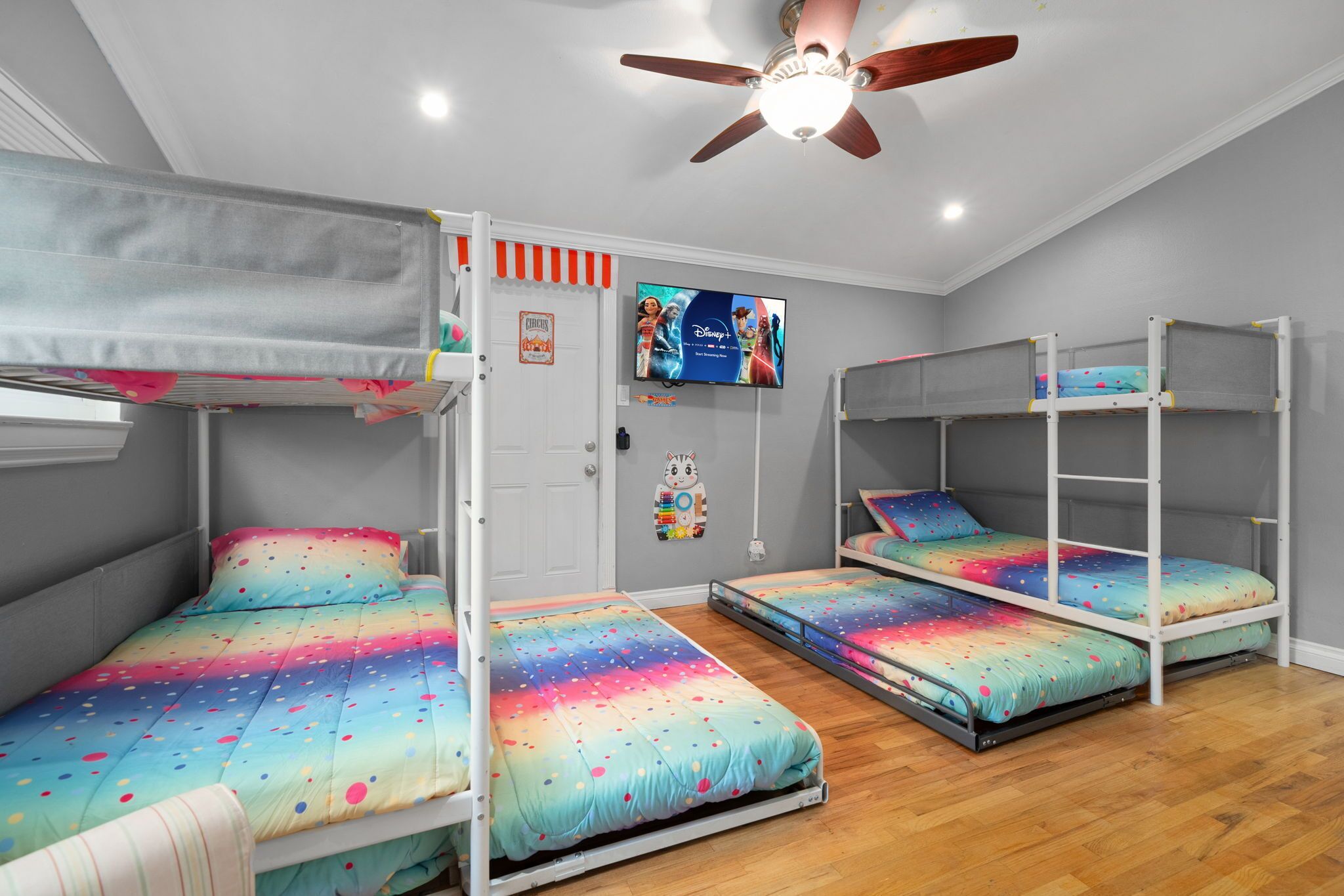 Ein Zimmer mit Etagenbetten, Deckenventilator und Fernseher an der Wand.
