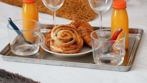 A tray with croissants, two glasses of water, and two orange juice bottles on a bed with a fluffy pillow. - TheBlueStay 143 - Superb cozy studio apartment (Paris)