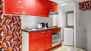 A compact kitchen with red cabinets, a white refrigerator, and a microwave. - TheBlueStay 143 - Superb cozy studio apartment (Paris)