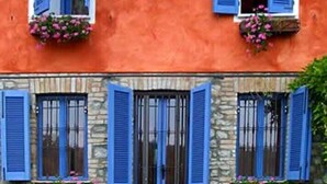 A building with two floors, each with blue shutters and flower boxes on the windowsills. - agriturismo il melo rosso   (Fortunago)