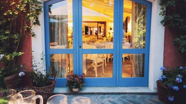 A blue glass door leading into a dining area with tables and chairs. - agriturismo il melo rosso   (Fortunago)