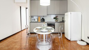 Een moderne keuken met witte kastjes, een magnetron en een koelkast.