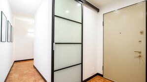Een gang met een schuifdeur van glas, een gesloten beigekleurde deur en ingelijste foto's aan de muur.