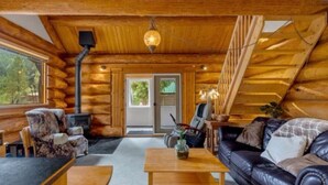 A log cabin interior with a fireplace, leather sofa, and wooden furniture. - Authentic lofted log cabin with hot tub (Kelowna)