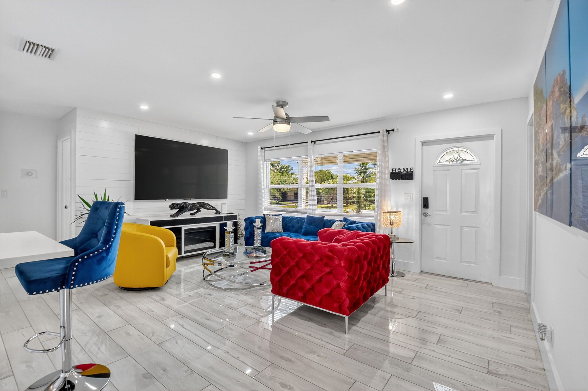 A modern living room with a flat-screen TV, a ceiling fan, a sofa set, and a dining area.