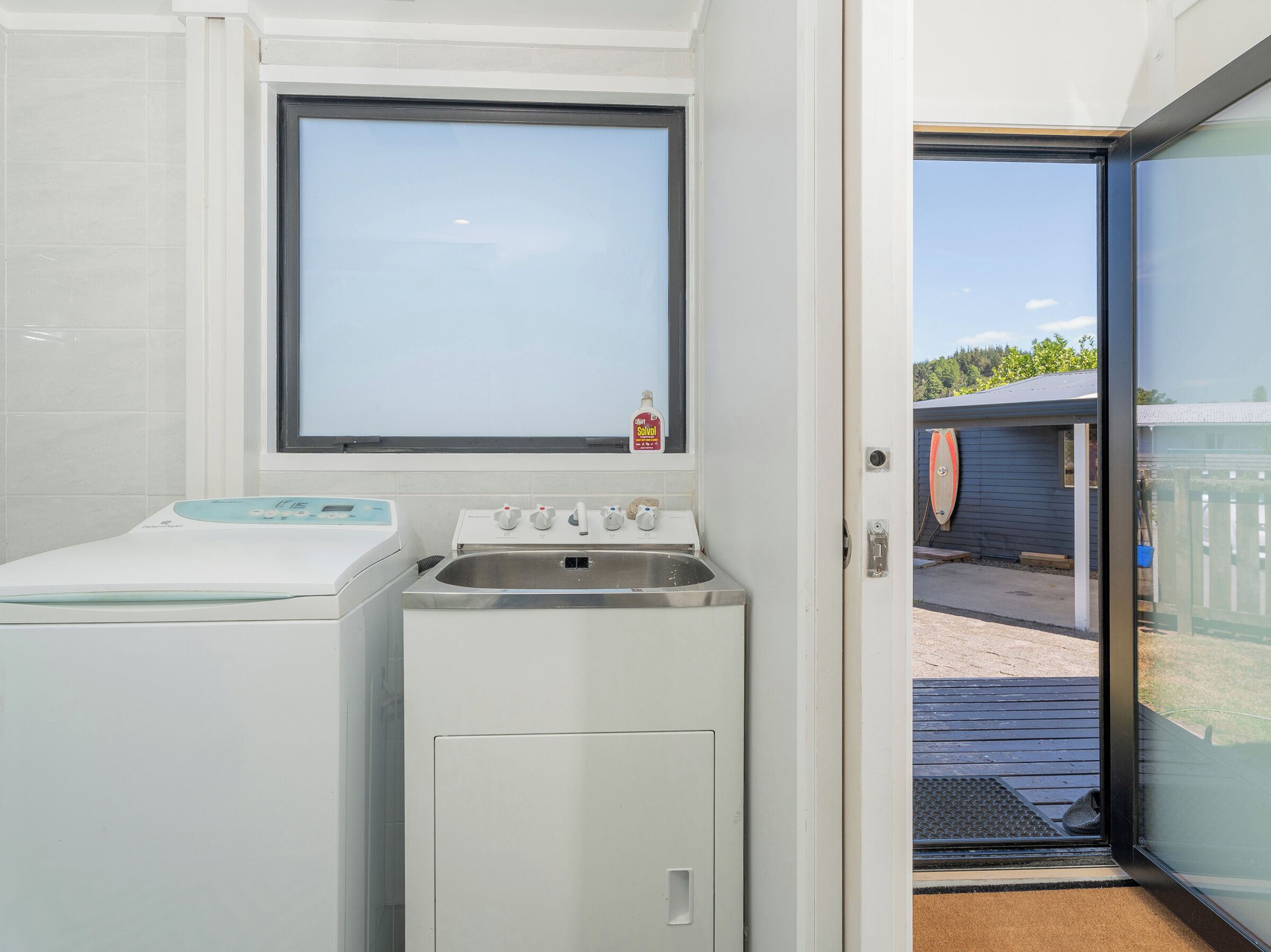 A compact laundry room with a washing machine, a dryer, and a sink.