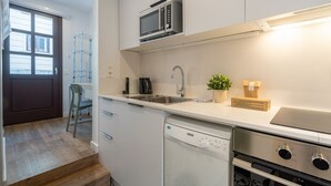 Une cuisine moderne avec des meubles blancs, un four à micro-ondes encastré, un lave-vaisselle et une cuisinière.