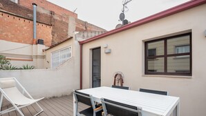 Une terrasse avec une table et des chaises, une porte et une fenêtre.