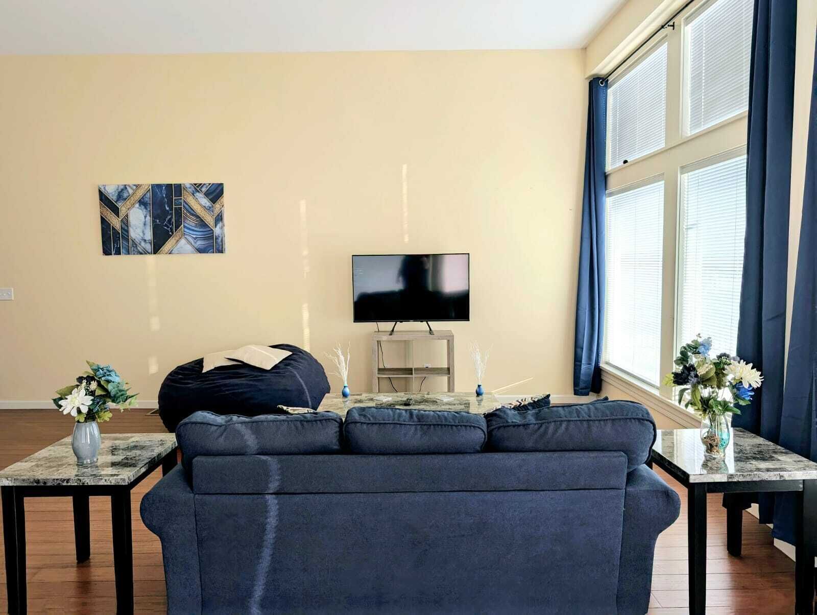 A living room with a dark blue sofa, a flat-screen TV, and a marble coffee table.