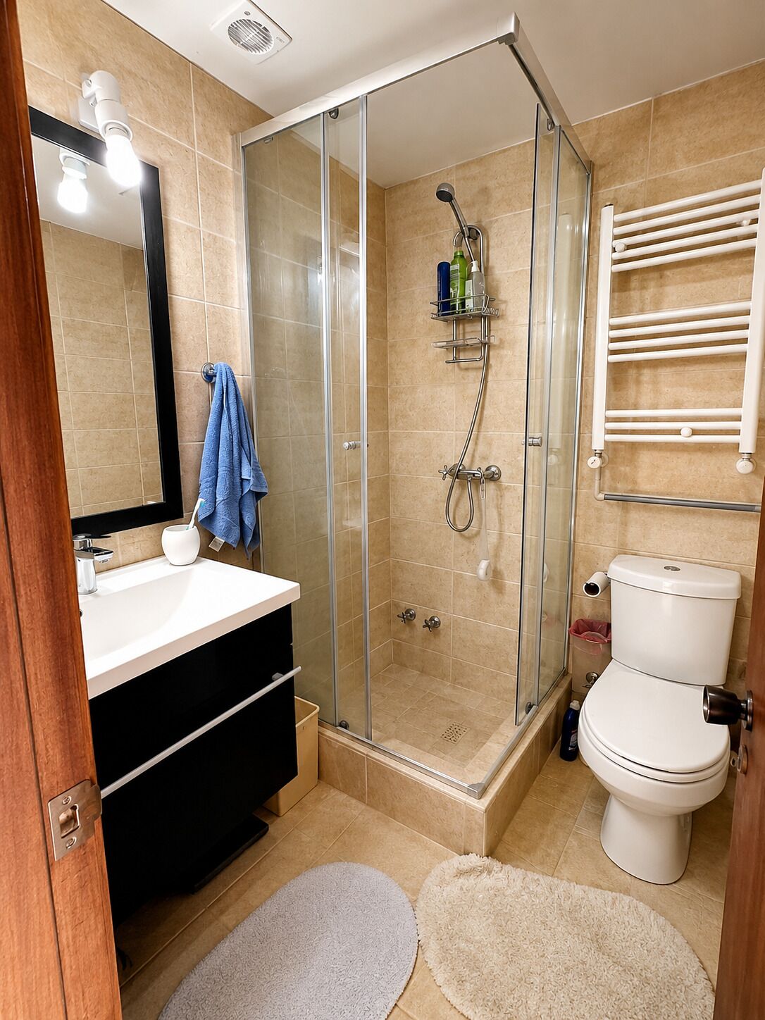 Un baño moderno con ducha de vidrio, lavamanos blanco y retrete.