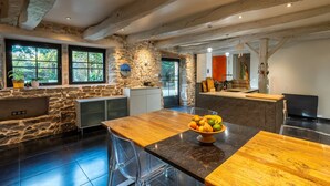 Una cocina moderna con paredes de piedra, encimeras de madera y un frutero en la isla.
