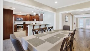 A modern kitchen with wooden cabinets, a central island, and pendant lighting. - 4BR/3BR - Spacious Home 4 Minutes From Beach (Largo)
