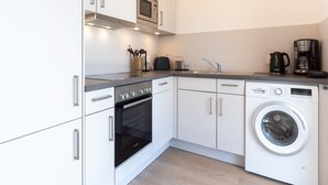 A compact kitchen with a built-in oven, microwave, and dishwasher. - Ferienwohnung in Busum (Büsum)