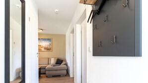 A hallway with a wooden bench, a grey sofa, and a wall-mounted coat rack. - Ferienwohnung in Busum (Büsum)