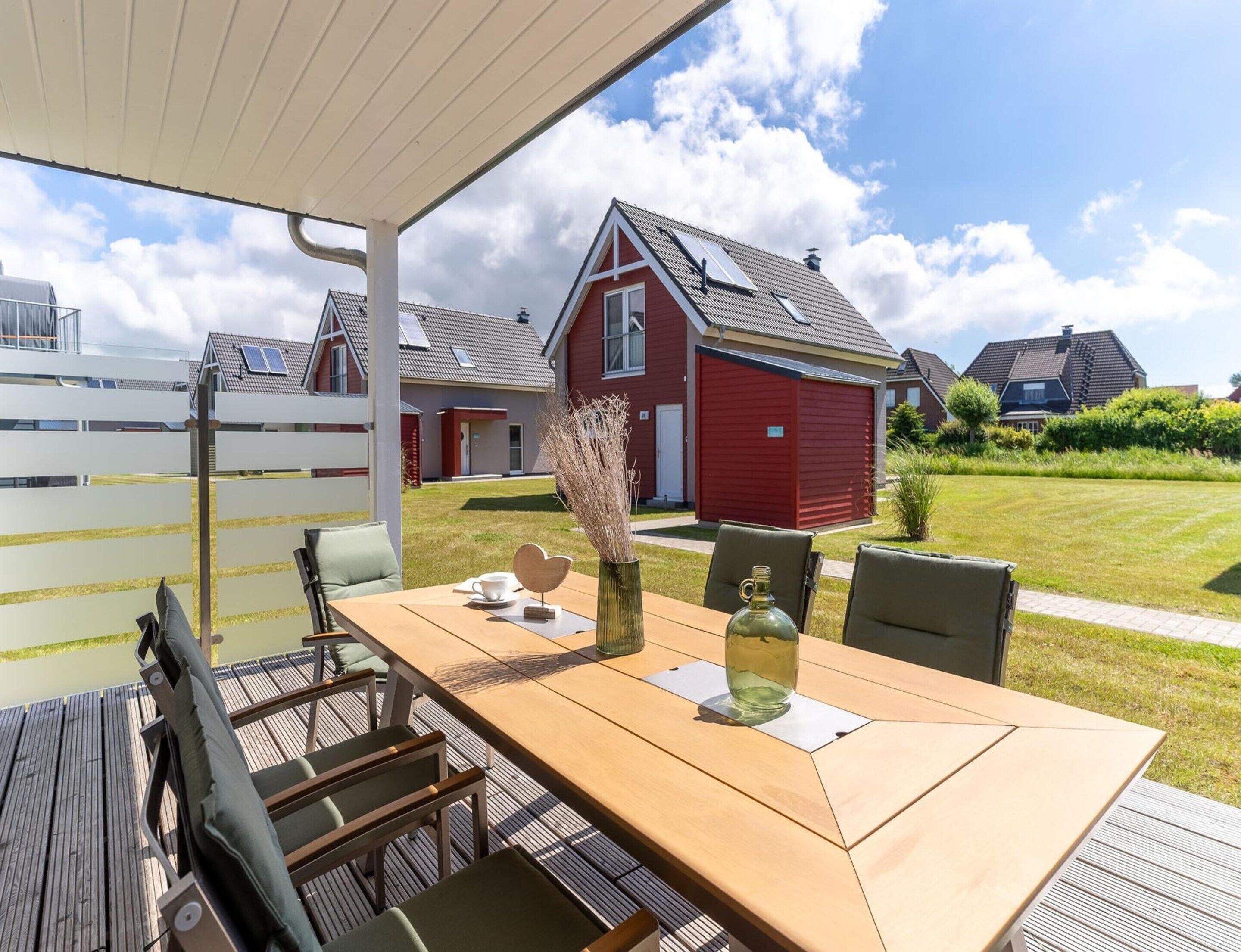 Un espace de restauration en plein air avec une table, des chaises et une vue sur les maisons en arrière-plan.