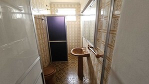 Un baño pequeño con inodoro, lavamanos y zona de ducha.