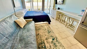 A bedroom with a bed, a sofa, a desk, and a TV.