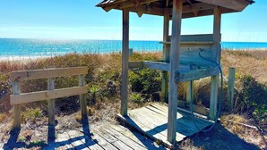 A wooden gazebo with a sloped roof overlooking a beach.