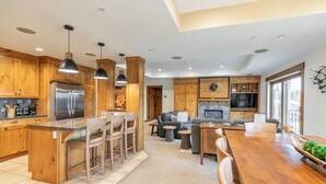 A modern kitchen with wooden cabinets, a stainless steel refrigerator, and pendant lighting. - Penthouse 2 Bedrm Suncadia Condo (Cle Elum)