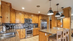 A kitchen with wooden cabinets, stainless steel appliances, granite countertops, and pendant lighting. - Penthouse 2 Bedrm Suncadia Condo (Cle Elum)