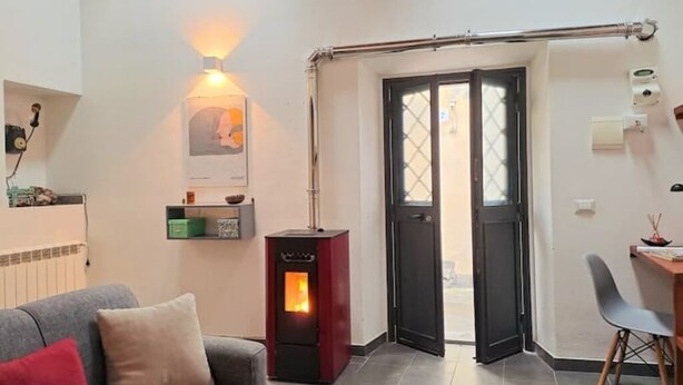A cozy living room with a sofa, a small table, a heater, and a door leading to an outdoor area.